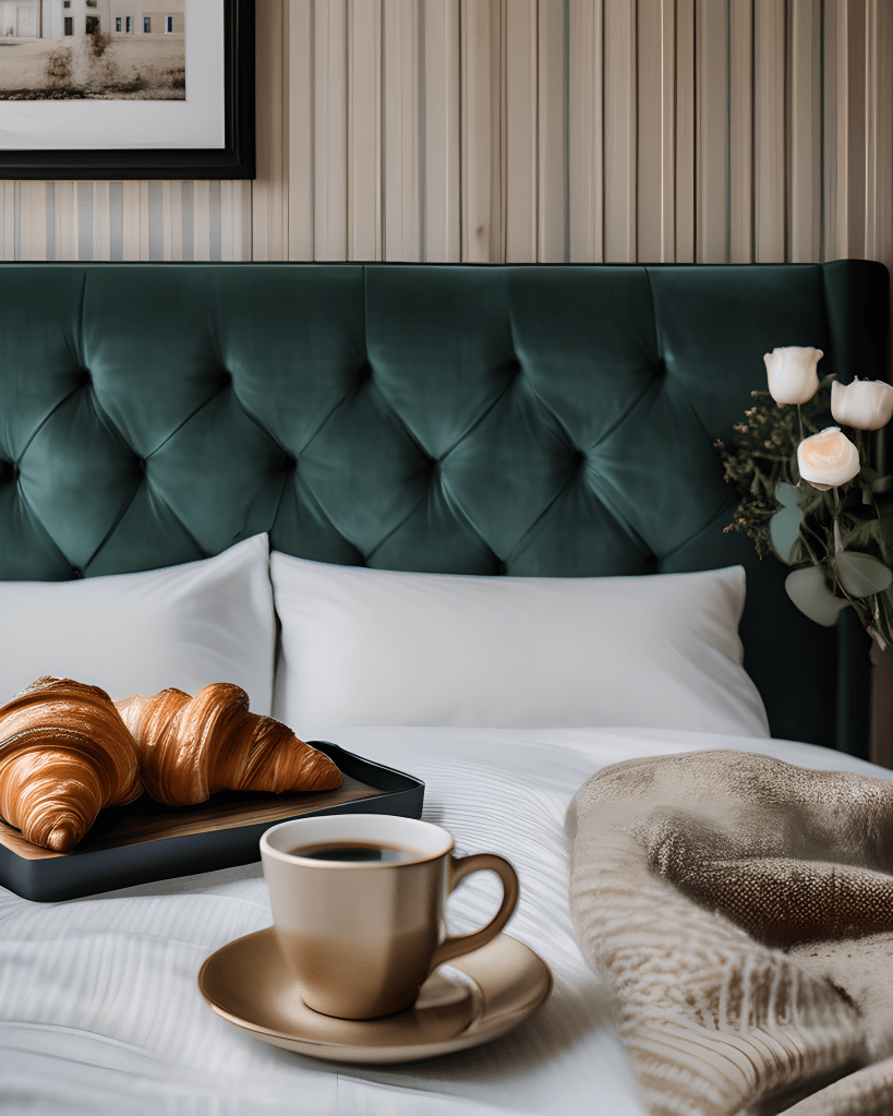 A close up of a bed with breakfast in bed consisting of croissants, coffee and white roses.